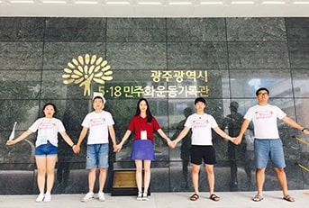 청년민주주의현장탐방에 선정된 청년들이 광주 518민주화운동기록관 앞에서 손을 잡고 사진을 촬영하고 있다